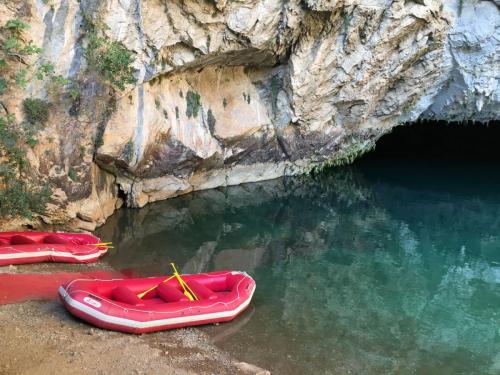 Rote Gummiboote im glasklaren Wasser im See der Altinbesik-Höhle mit Spiegelungen der Felsen.